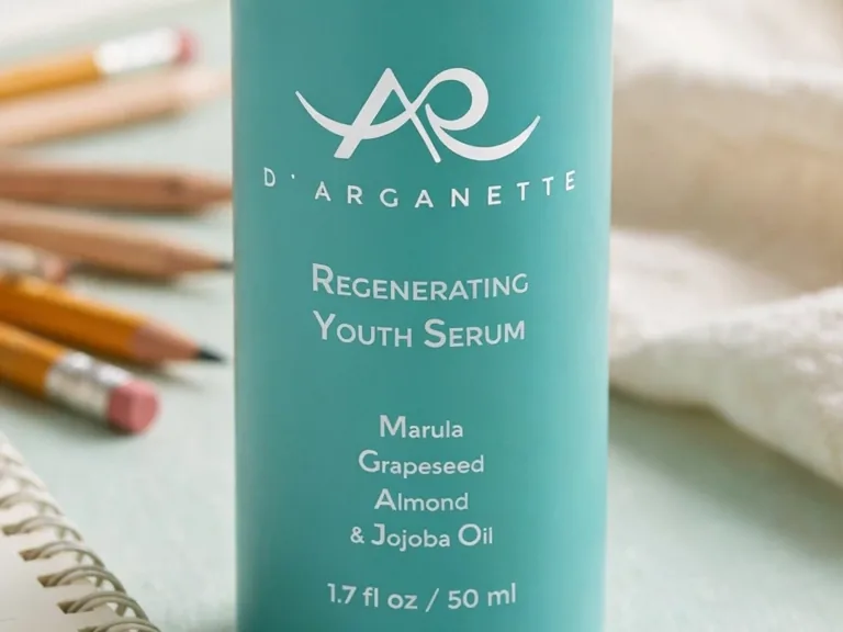 Regenerating Youth Serum bottle label up close on a mint desk with pencils and a notebook