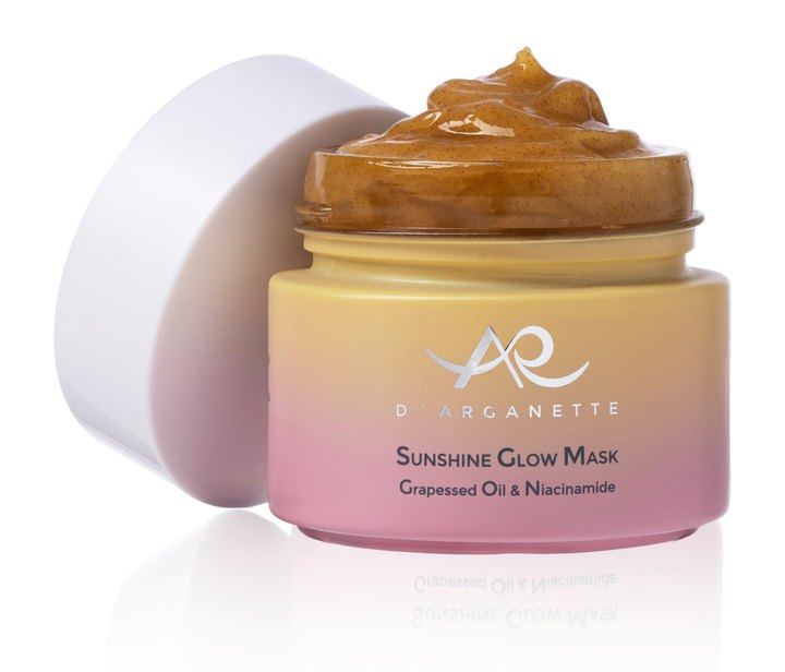 D'Arganette Sunshine Glow Mask jar in a yellow to pink gradient with the lid leaning beside it